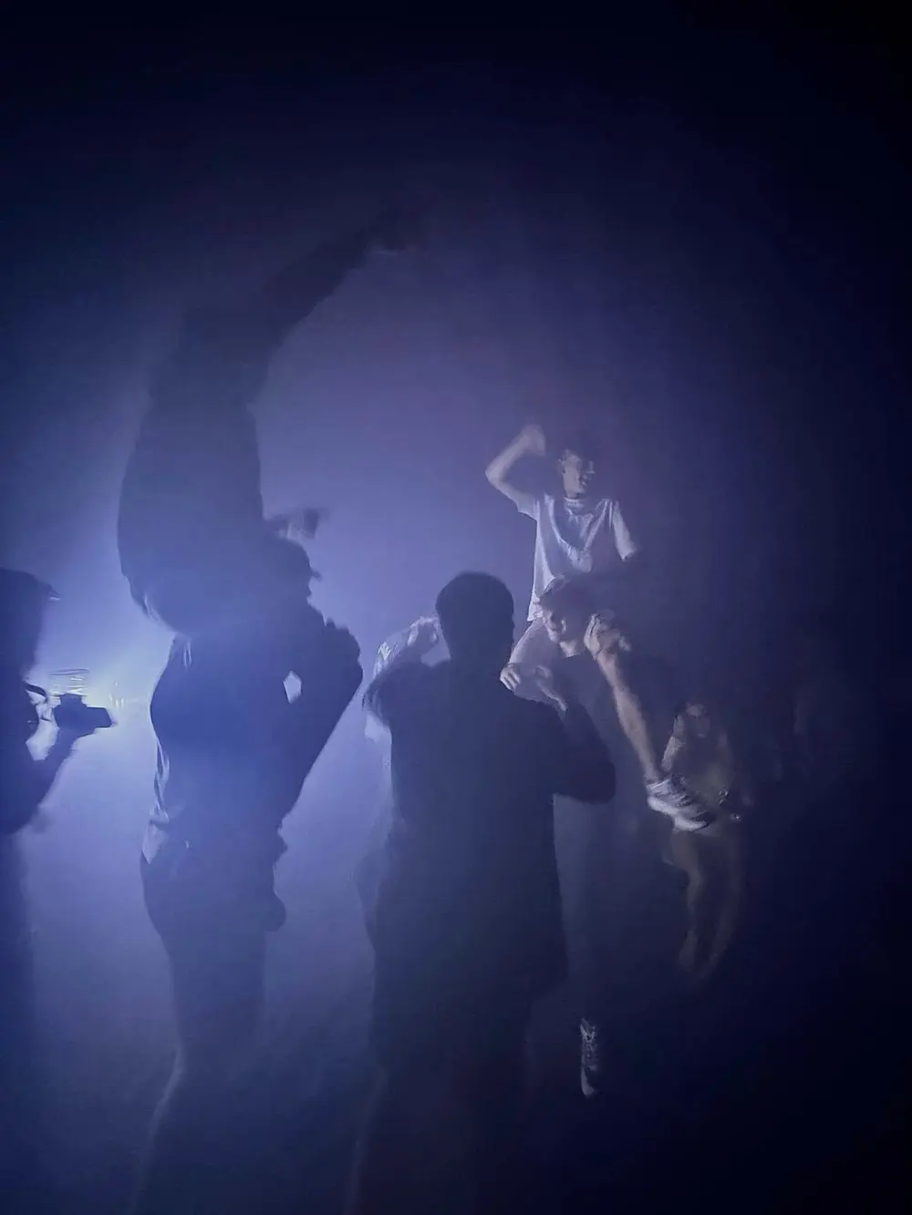 Guests dancing in smoke and blue light inside the club