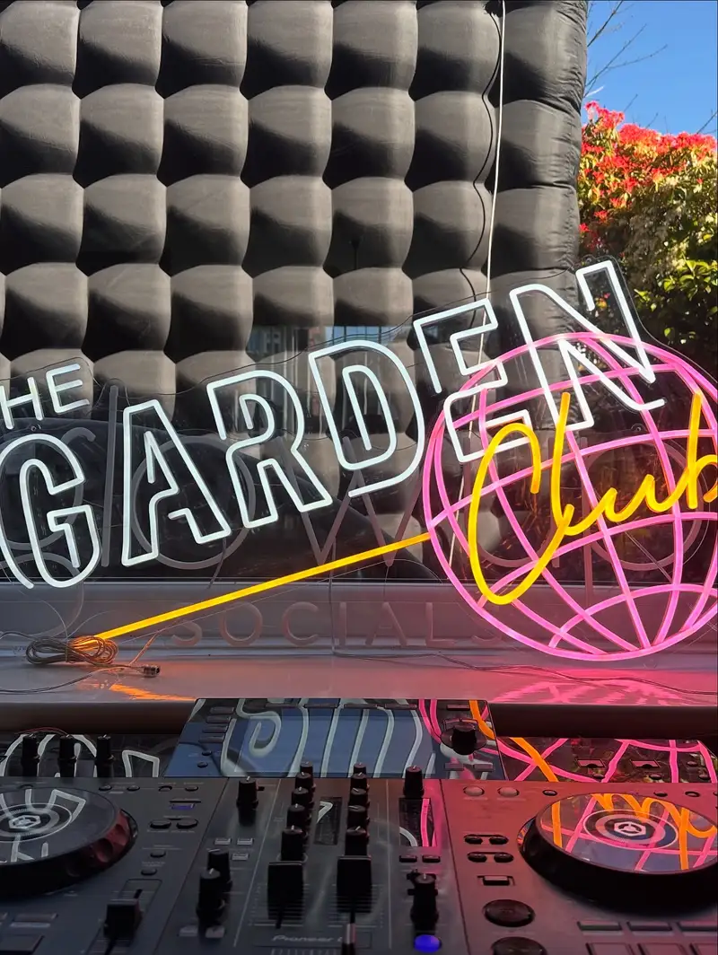 DJ decks under The Garden Club neon sign