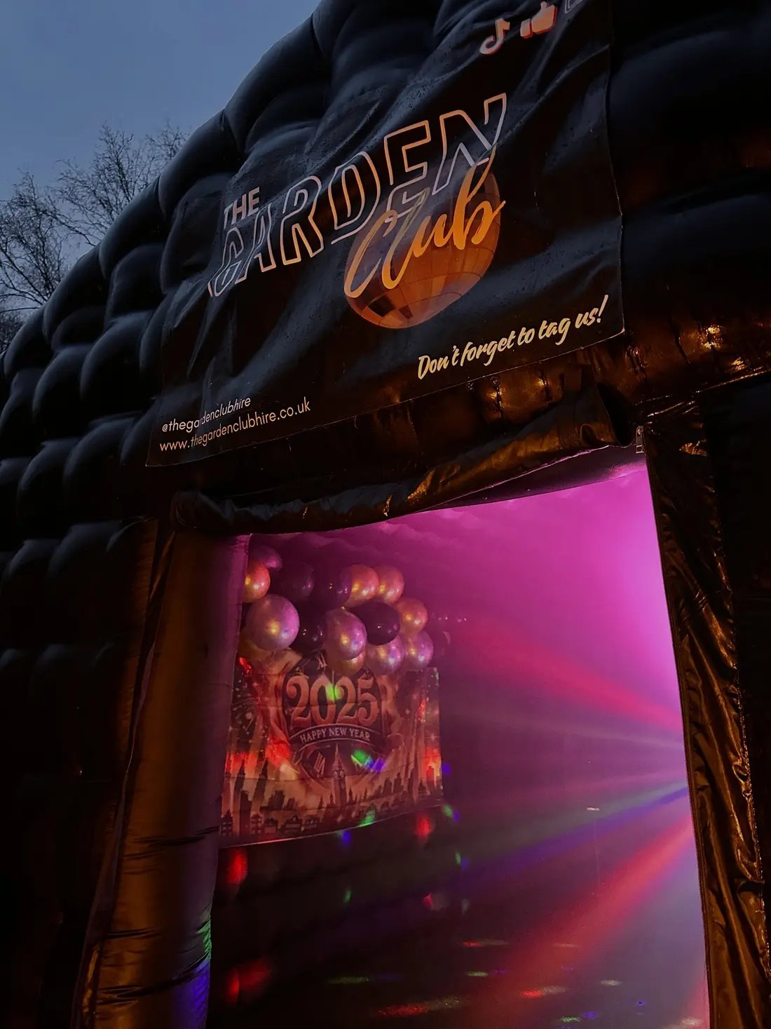 The Garden Club entrance lit pink and gold from inside