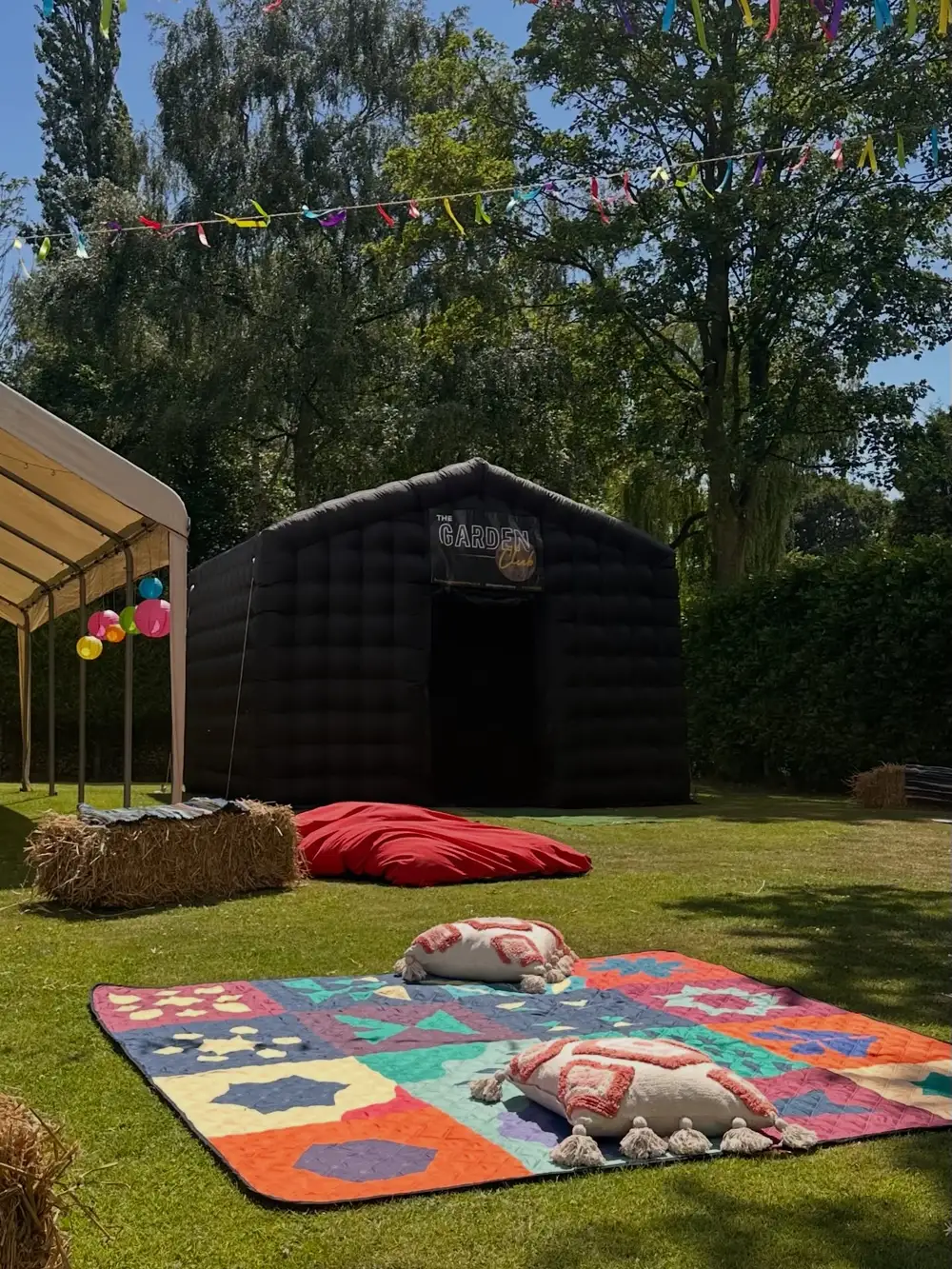 Festival style garden set-up with a gazebo, hay bales, rugs and the black nightclub