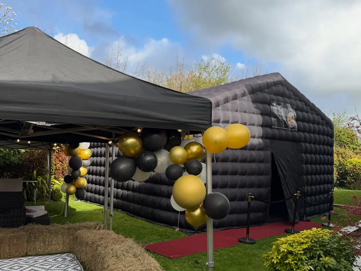 Black gazebo, gold balloons and hay bales next to the nightclub