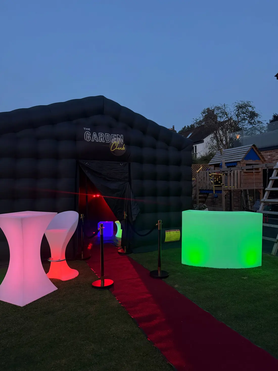 LED poseur tables and glowing cube seats outside the club on a red carpet at night