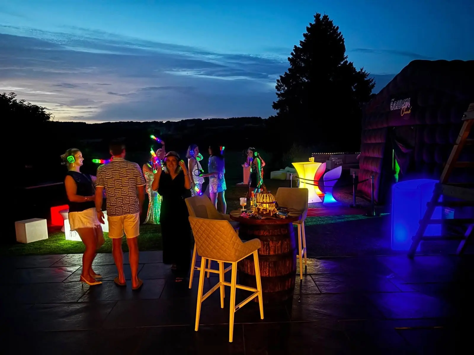 Guests around LED furniture and a bar outside the club at night