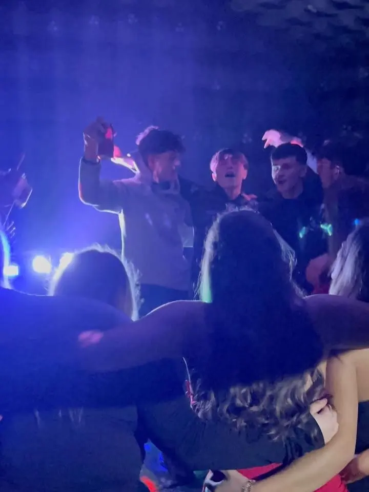 A crowd with their hands up under the lights inside the club